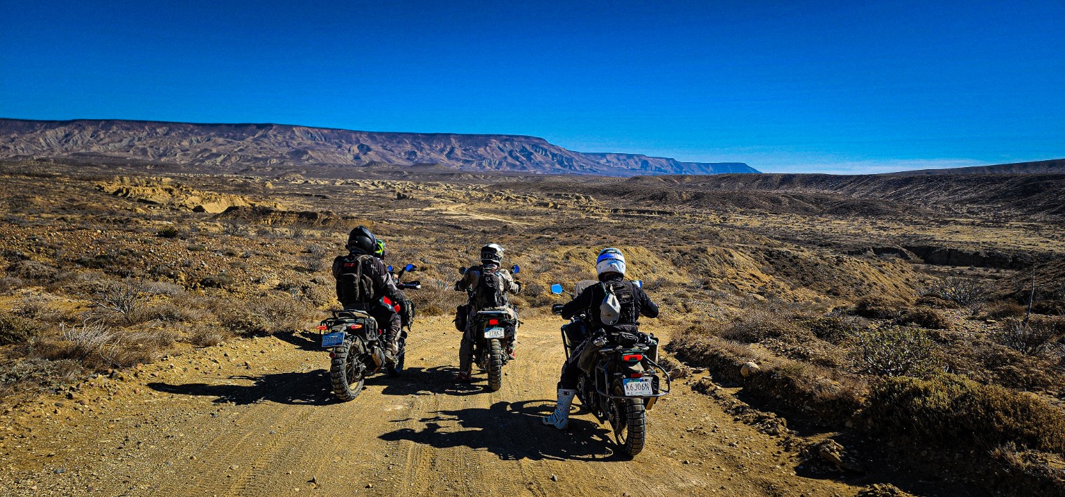 Tres pilotos en motocicleta frente a los caminos y sierras de Baja California
