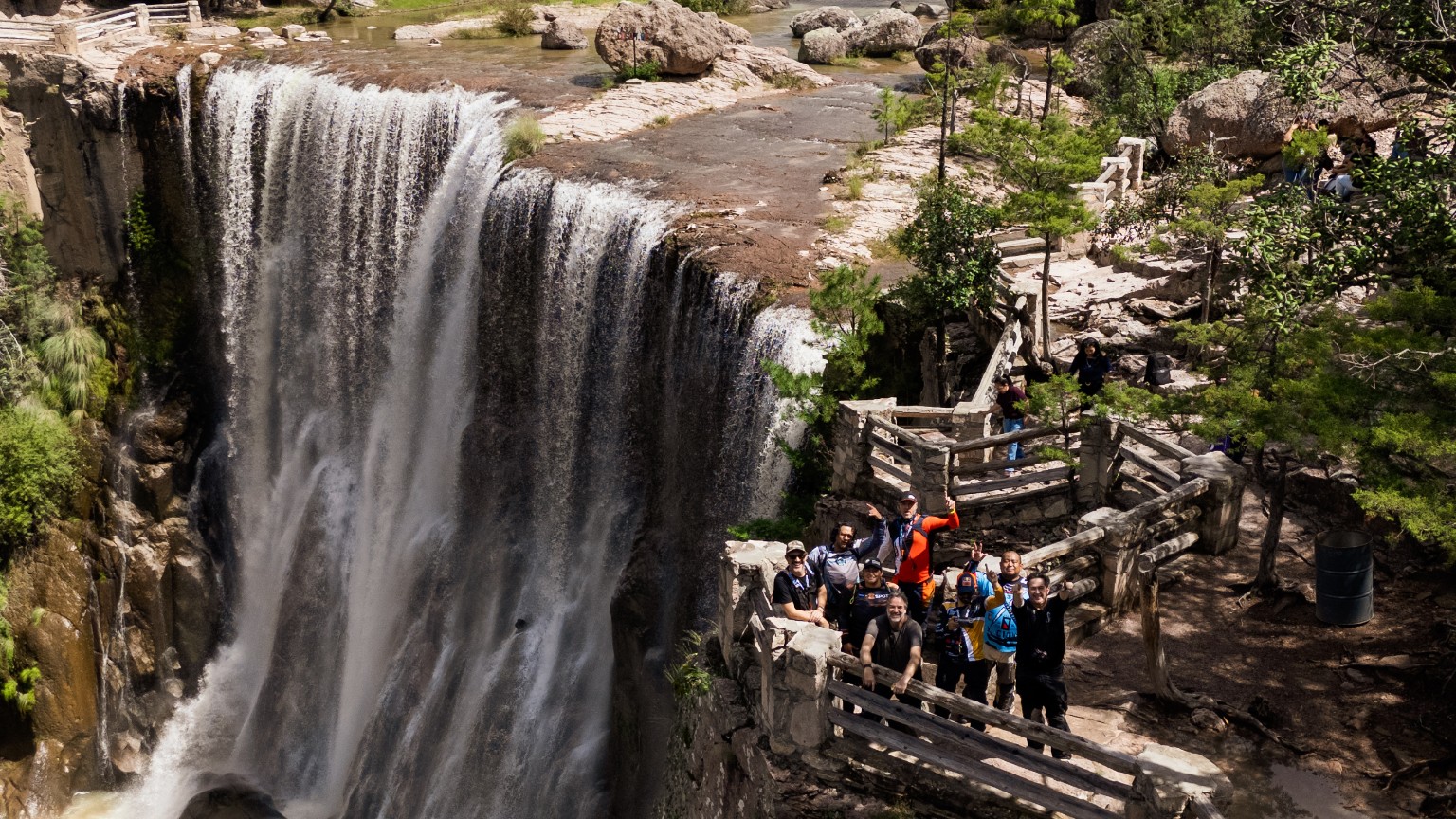 Grupo de viajeros en un mirador junto a una cascada de la sierra
