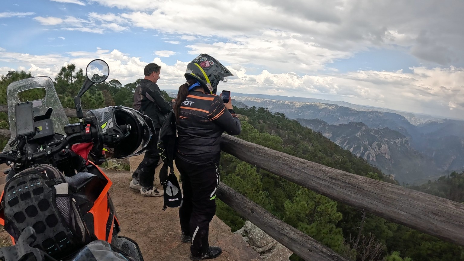 Pilotos y motocicletas en un mirador frente a las barrancas y montañas