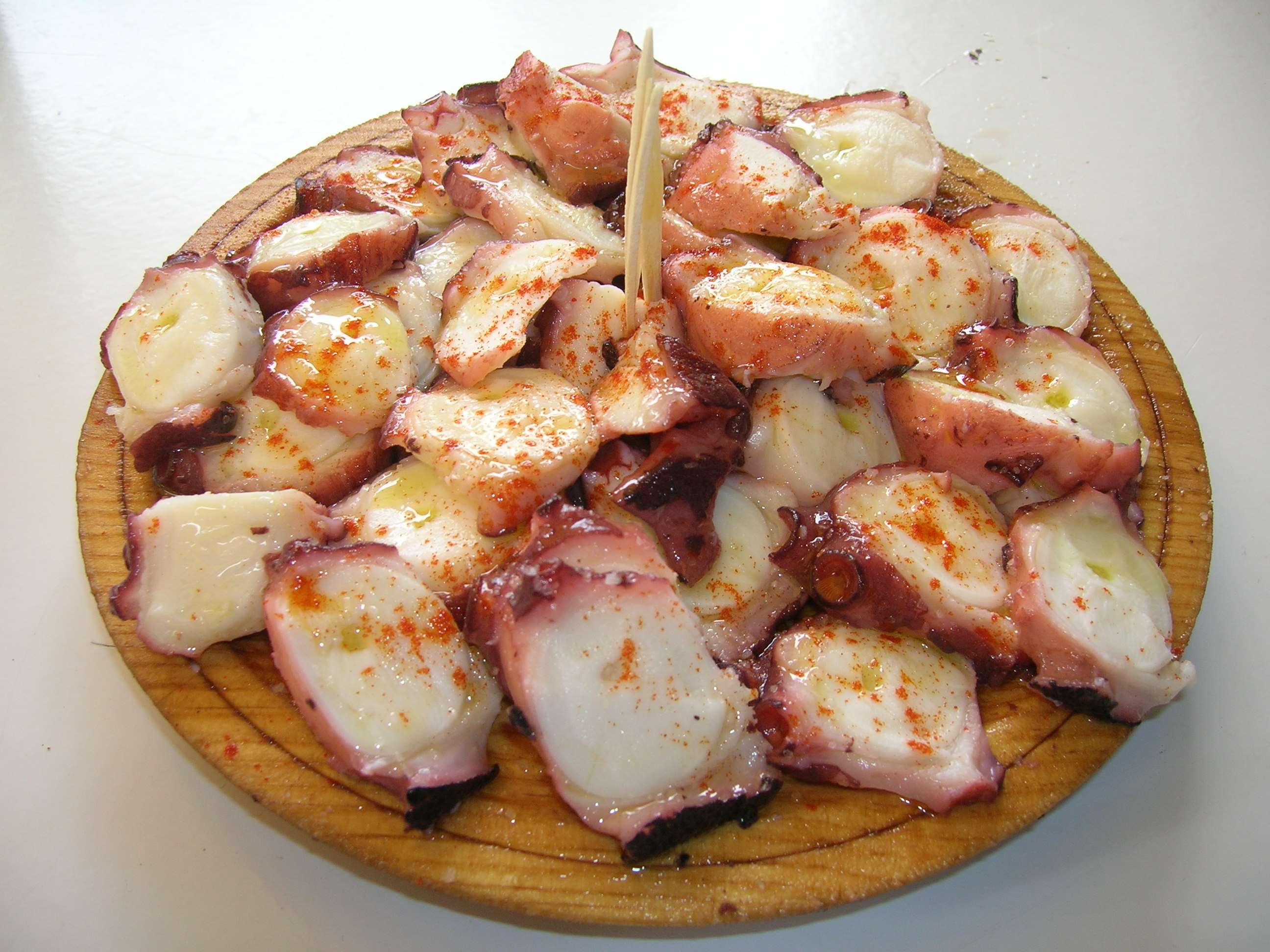 Pulpo á feira gallego servido en plato de madera con pimentón y aceite