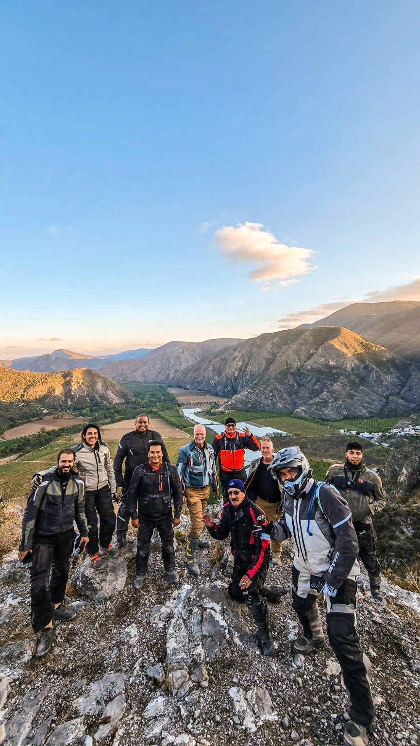 Grupo de pilotos en un mirador sobre un valle rodeado de montañas