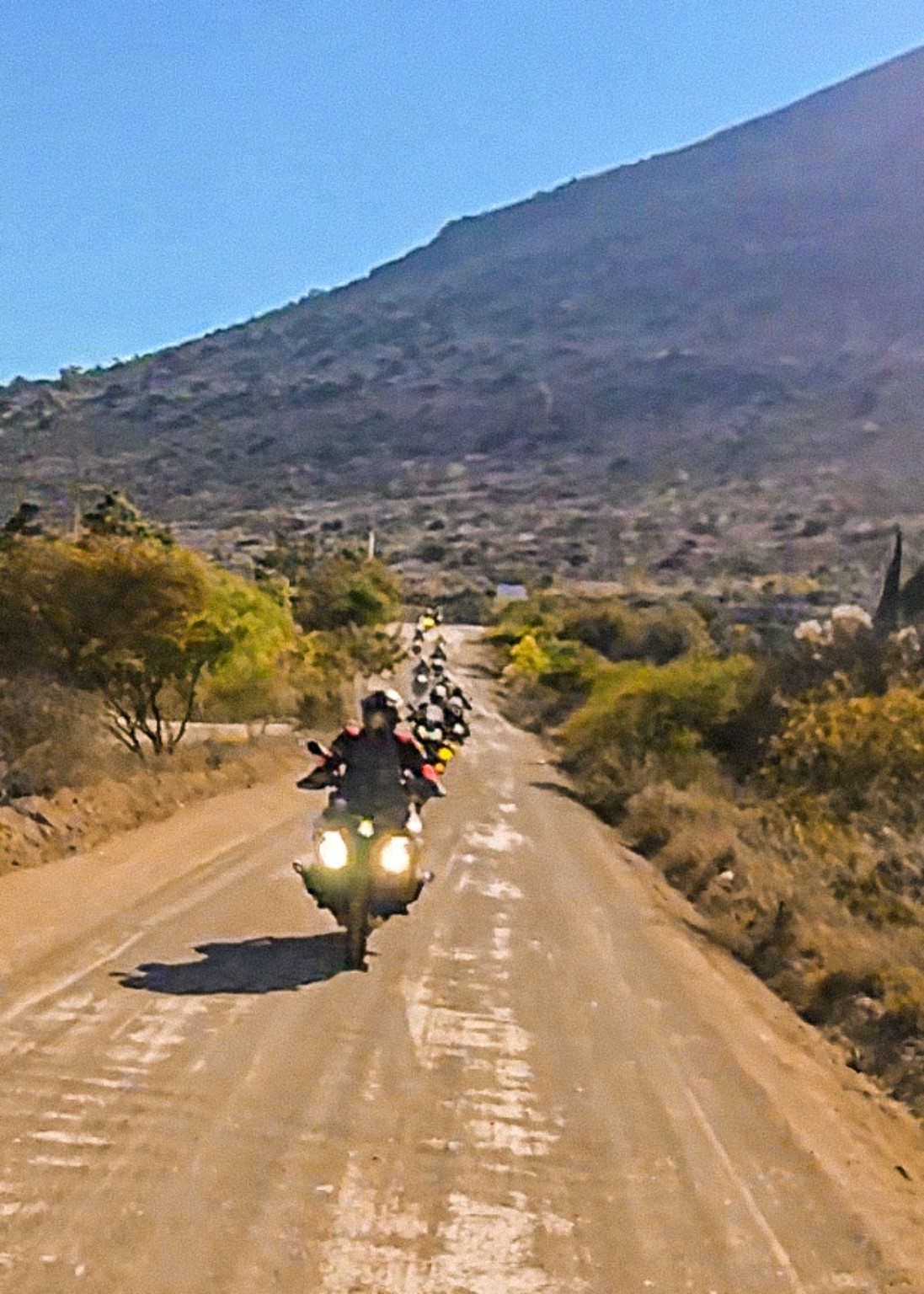 Piloto en motocicleta sobre un camino de terracería entre montañas