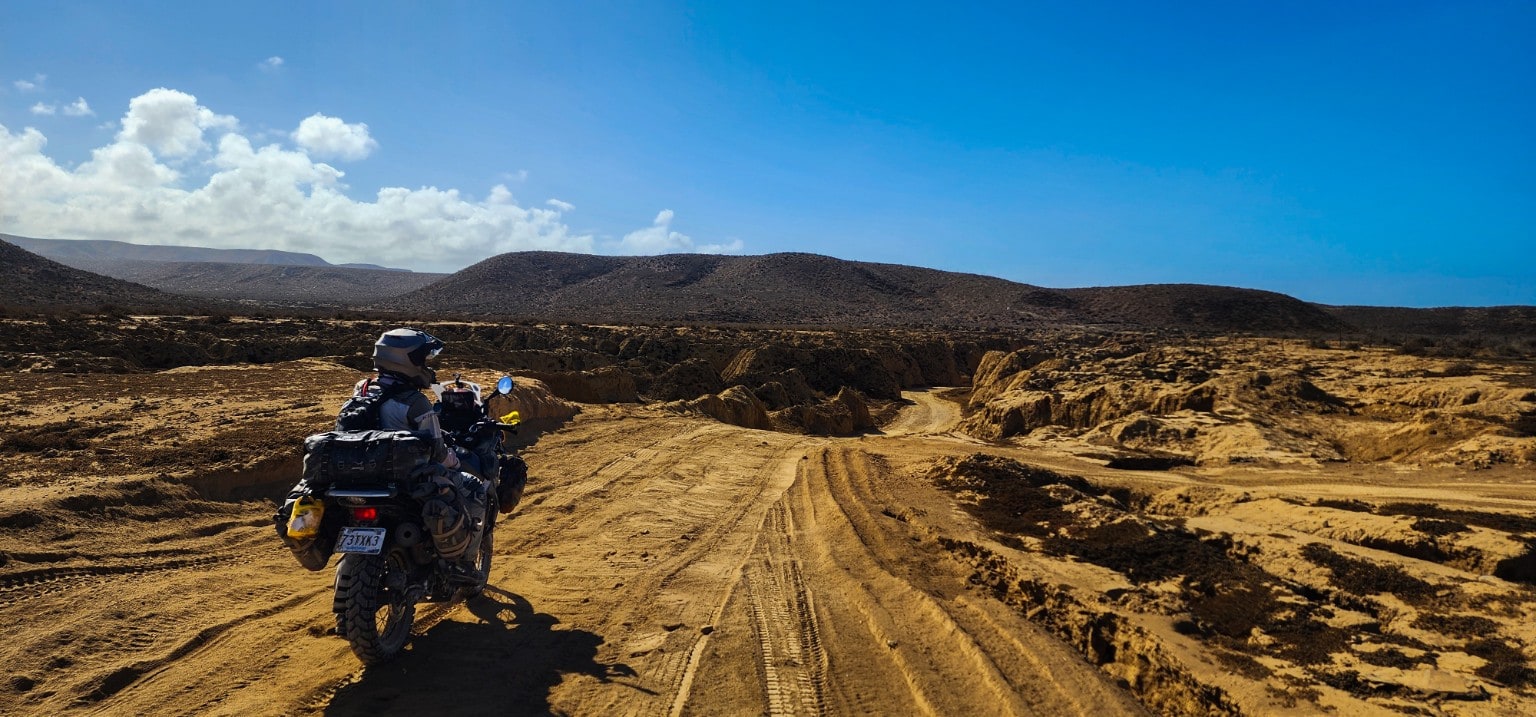 Motociclista frente a un camino entre las sierras y el desierto de Baja