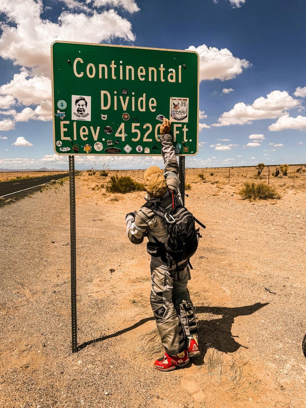 Mike colocando un sticker MotoMike en el letrero del Continental Divide