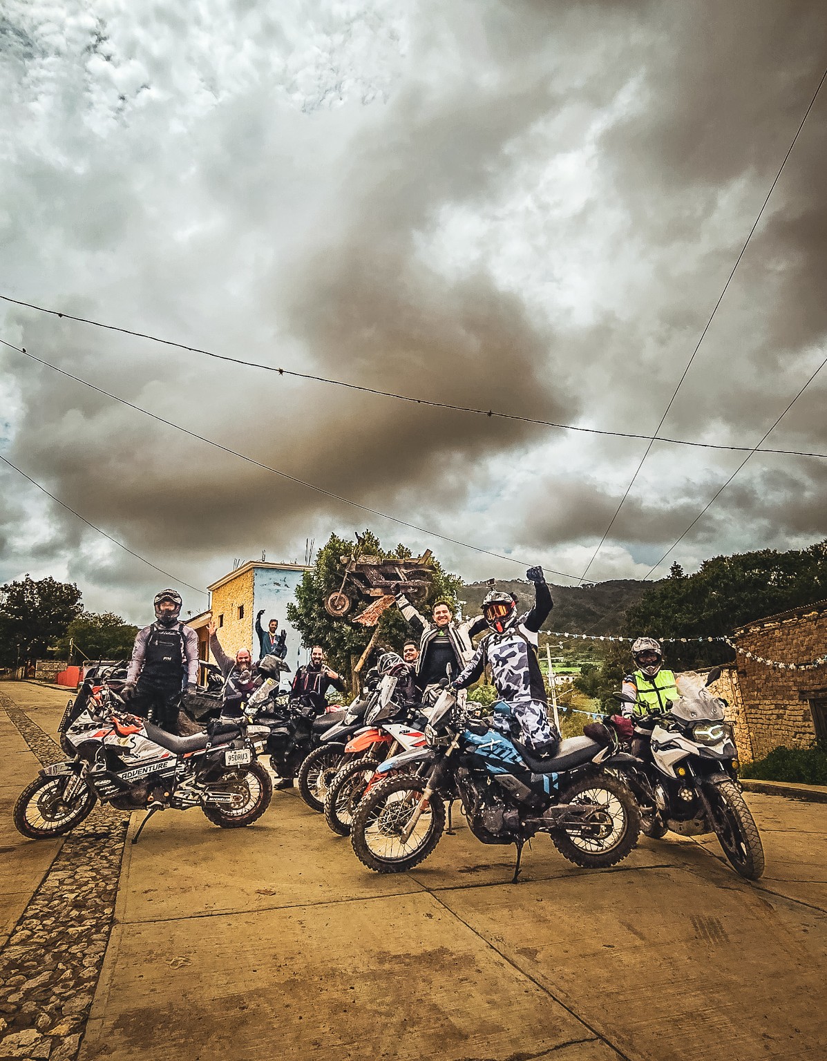 Grupo de pilotos con sus motocicletas reunidos en una plaza de la sierra