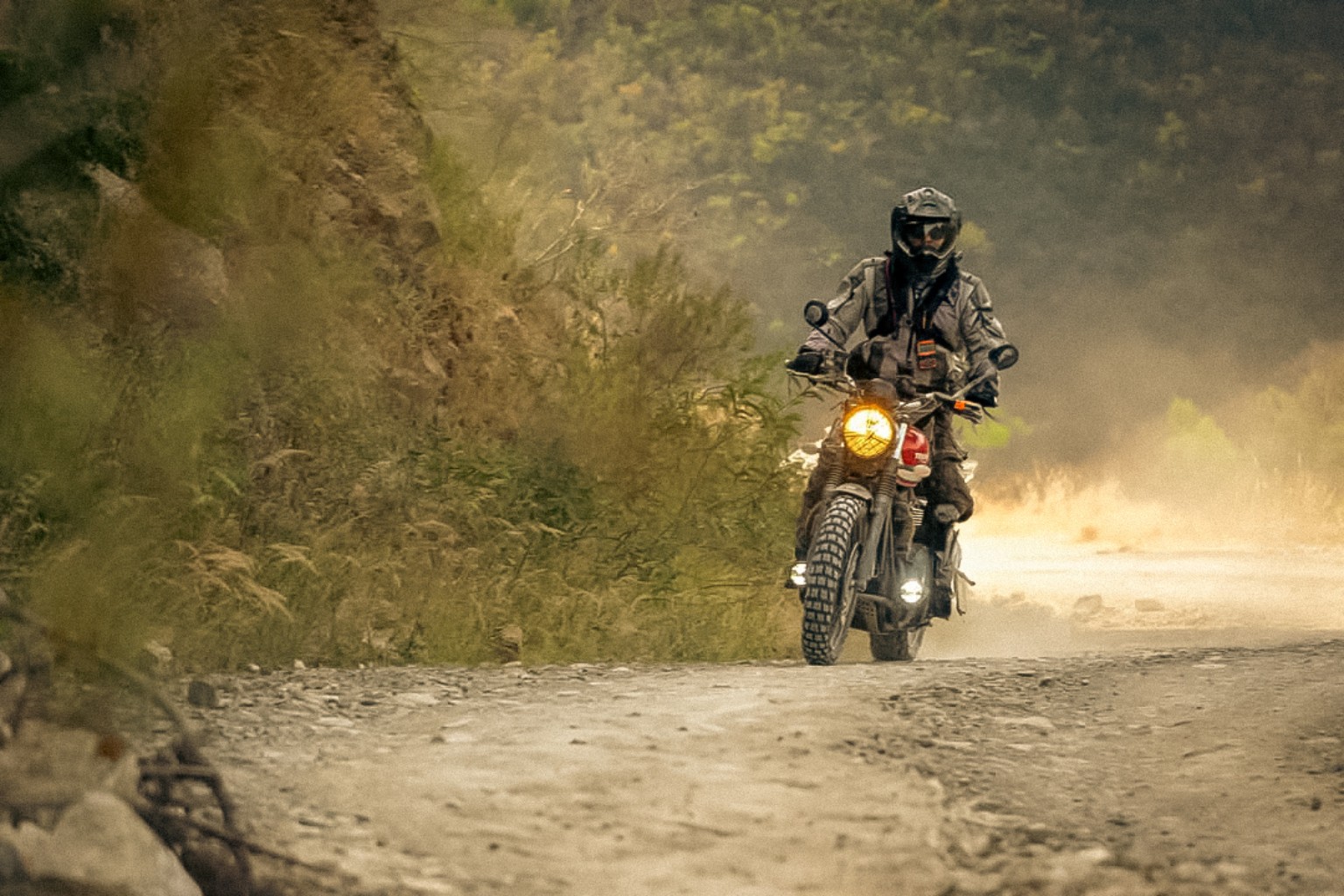 Piloto en motocicleta recorriendo una terracería de la sierra entre polvo y vegetación